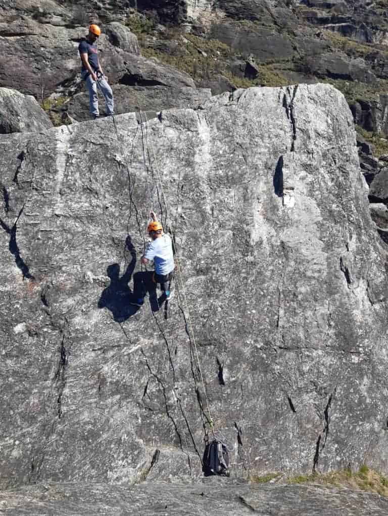 Climbers practicing glacier travel and crevasse rescue techniques on a large rock face.
