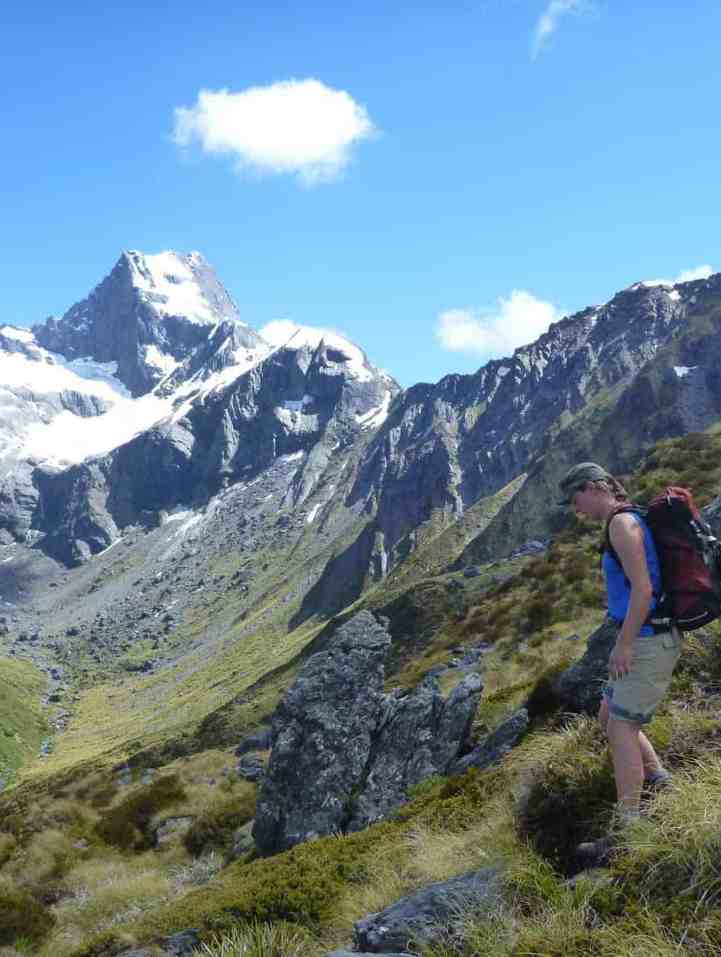 Hiker on Gillespie Pass with snow-capped peaks in the background.